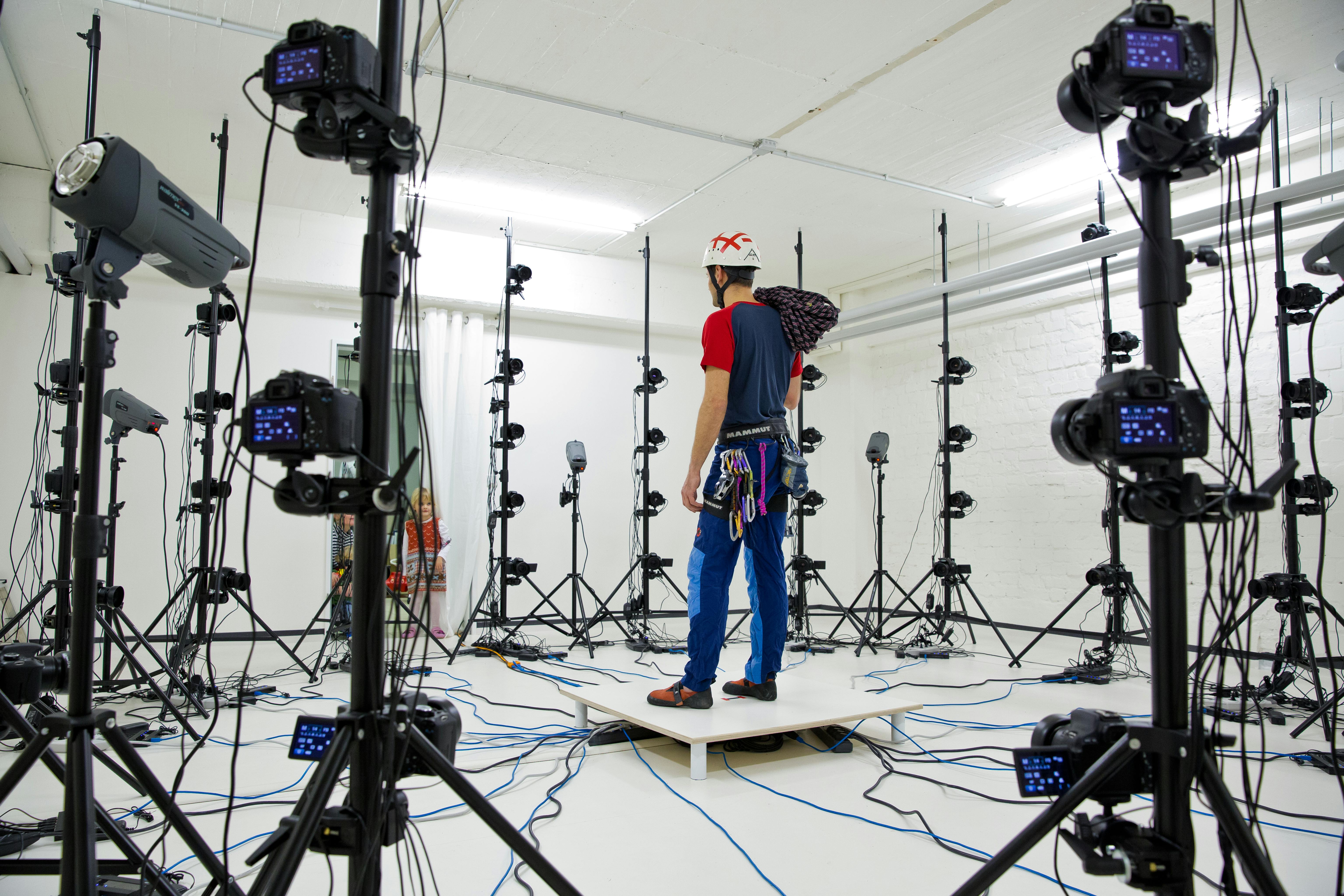 Man in a studio surrounded by multiple cameras and tripods for a photoshoot.